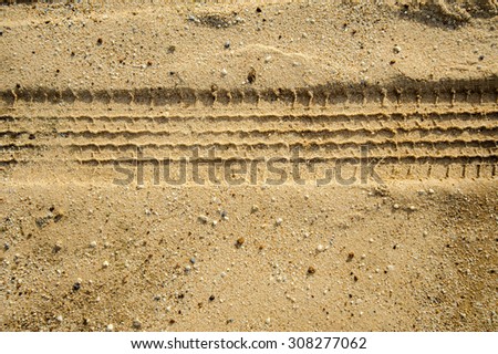 Car tyre print on flat brown sand floor