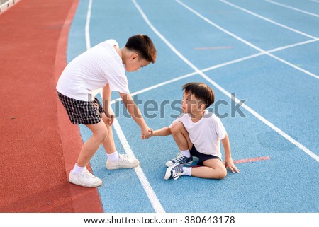Young asian boy give hand to help accident boy during running on the blue track.
