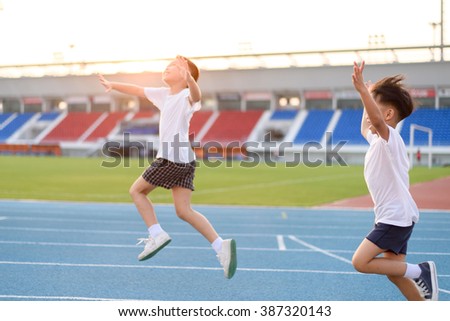 Young Asian boy running on blue track in the stadium and happy during day time to practice himself.