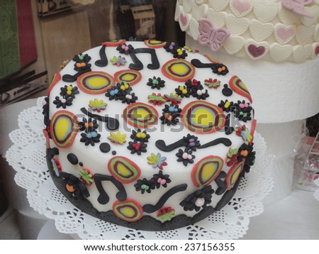 Freshly baked delicious artistic Italian Arts and Crafts cake decorated with music notes and colorful circles on white marzipan icing.