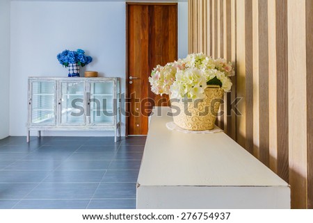 Vase with plastic flowers placed on a cabinet in the corner of the living room.