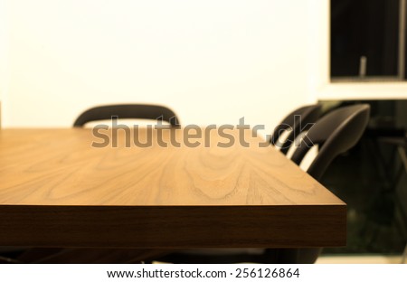 Dark brown wooden dinning table edge with black chair background