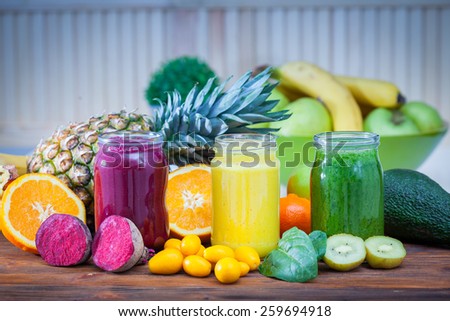 Blended green,yellow and purple smoothie with ingredients selective focus