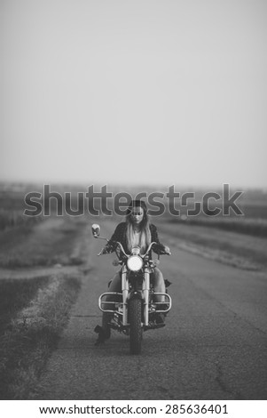 Beautiful woman on the motorcycle. Retro Black and white filter.
