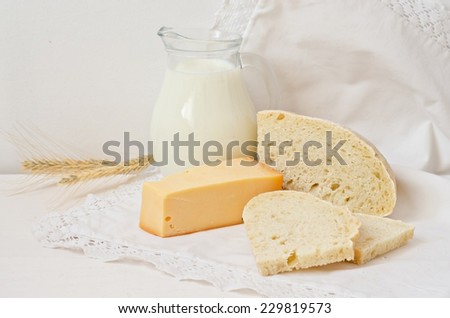 Still life with tasty milk, bread and cheese  on white wooden table