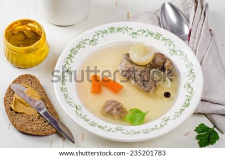 Broth with beef in vintage plate on wooden table
