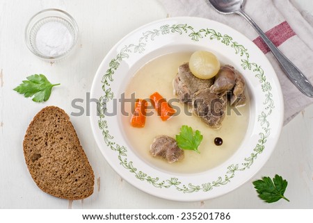 Broth with beef in vintage plate on wooden table