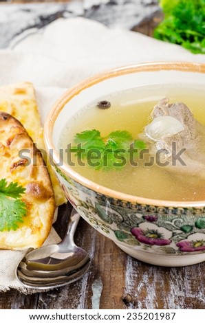 Broth with beef in bowl on dark wooden background