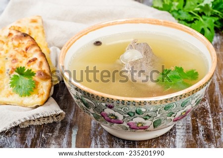 Broth with beef in bowl on dark wooden background