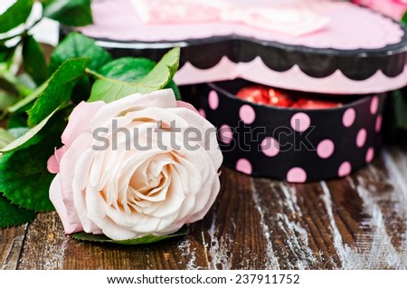 Pink rose with heart shaped box of chocolate candies. Selective focus on rose