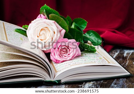 Pink roses on opened muslims book Quran. Selective focus on roses