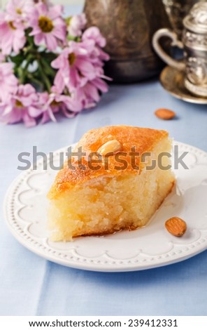 Basbousa (namoora) - arabian semolina cake with almonds and honey syrup on cotton blue background