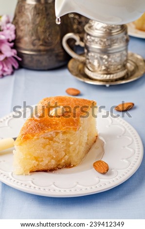Basbousa (namoora) - arabian semolina cake with almonds and honey syrup on cotton blue background