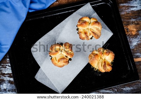 Homemade freshly baked rolls on parchment and  scratched black  try, wooden background. Selective focus