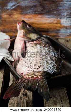 Raw fish pelengas in vintage iron tray on wooden background. Selective focus on fish tail