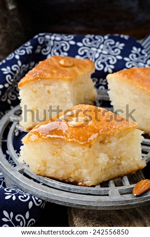 Basbousa (namoora) - arabian semolina cake with almonds and honey syrup on iron support. Slices of cake