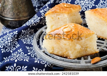 Basbousa or namoora - arabian semolina cake with almonds and honey syrup on iron support