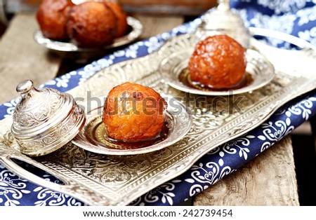 Gulab jamun - fried sponge balls in sugar syrup on iron tray and wooden background. Indian cuisine. Selective focus
