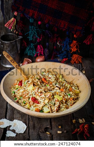 Biryani with chicken and vegetables in iron bowl on vintage wooden background