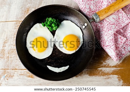 Smiling  Happy Face Frying Eggs breakfast with parsley in iron vintage pot on wooden table. Selective focus