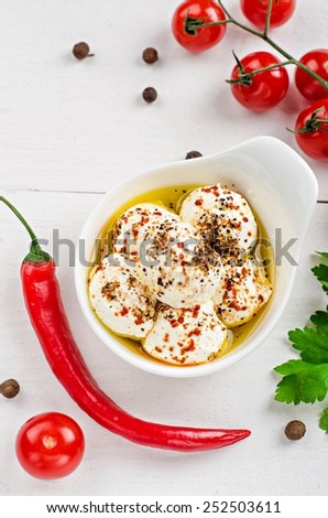Laban - yogurt or cheese balls with olive oil and spices in white plate near tomatoes, parsley , chili pepper  on wooden baskground. Arabic cuisine