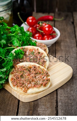 Arabian or turkish Mini pizza - lahmacun with parsley and tomatoes on wooden background