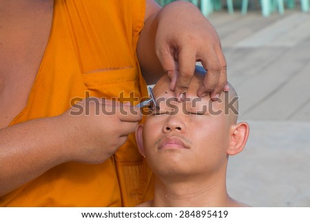 Samut Prakan -Thailand-May-24- : Thai man gets his head shaved by a monk with intend during a Buddhist ordination ceremony on May 24, 2015 in Samut Prakan, Thailand.
