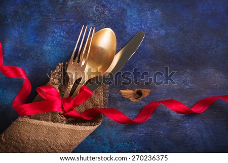 Vintage tableware decorated with red ribbon on blue wooden table, selective focus