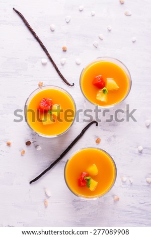 Dessert panna cotta with fresh berries and vanilla pods on wooden background, selective focus. Top view