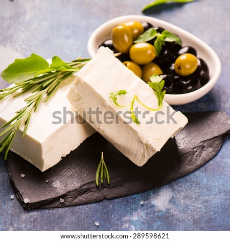Feta cheese with fresh herbs, black and green olives, selective focus. Square image