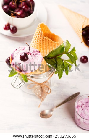 Wafer cones with homemade cherry ice cream, served with mint and fresh sweet cherry. Selective focus