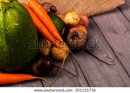 Harvest fest. Fresh organic vegetables: carrot, potato, sugar beet and vegetable marrow on rustic wooden background. Selective focus. Toned image