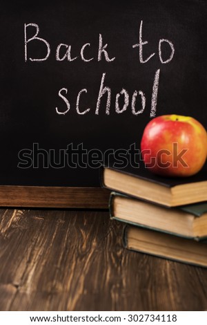 Back to school concept. Blackboard with a chalk, old books, apple and plastic letters. Vintage style. Selective focus