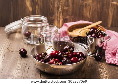 Rich harvest of sweet cherry. Ingredients and kitchen utensils for jam on rustic dark wooden background. Selective focus