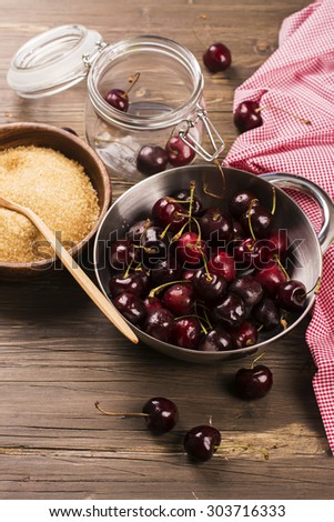 Rich harvest of sweet cherry. Ingredients and kitchen utensils for jam on rustic dark wooden background. Selective focus