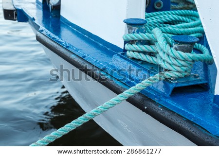 Iron Berth Holding White Boat Lines on a White and Blue Boat Near Shore
