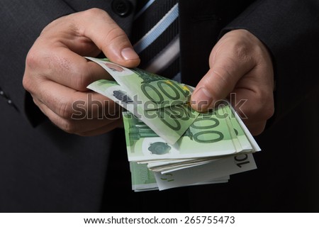 Man in black suit counts euro money