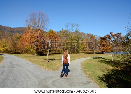 Girl walking on the road, beautiful autumn October day.