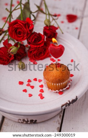 Mini muffins, candle in the shape of hearts and red roses.