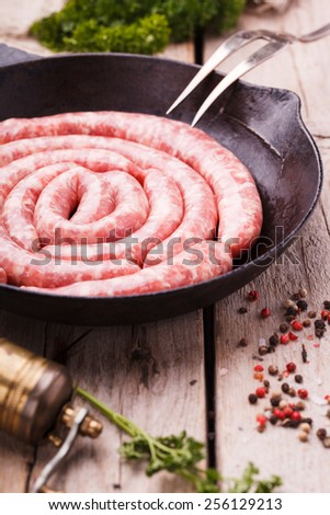 Sausages raw homemade frying in a cast iron skillet,composition spiral.selective focus
