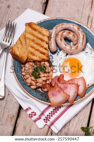 English breakfast with fried eggs, bacon, sausages, beans, toasts. selective focus.
