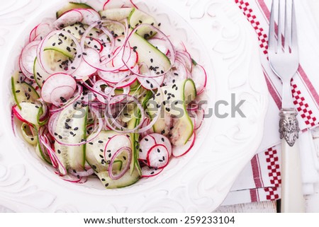Salad with cucumber, radishes, red onion and black sesame seeds.