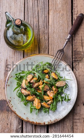 Salad with mussels and arugula on a glass plate with olive oil and lemon.selective focus