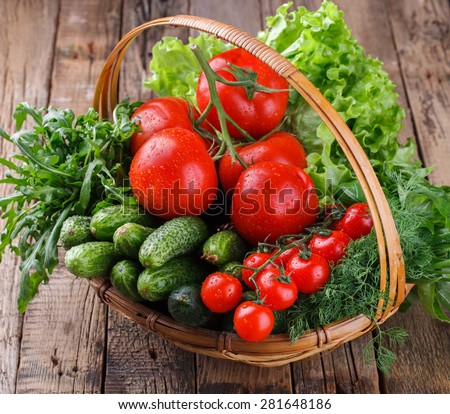 Freshly harvested organic vegetables in a basket.Tomatoes, cucumbers,cherry tomatoes, lettuce, dill,arugula. selective focus
