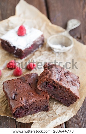 Chocolate brownie with raspberries, sprinkled with powdered sugar.