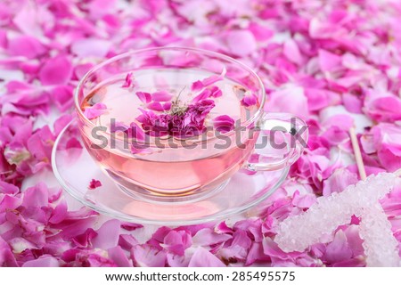 Tea with rose petals in a glass Cup with sugar crystals on the shelf. Rose water.