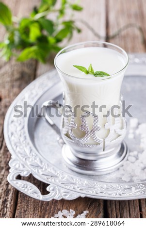 A glass of buttermilk and a bunch of mint on the tray.Milk product. selective focus