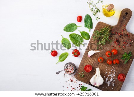 Organic vegetarian ingredients, olive oil and seasoning on rustic wooden cutting board over dark vintage background with space for text.Healthy food, or diet nutrition concept.selective focus.