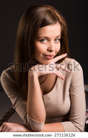 Portrait of a young woman looking at you with a chin on her hand