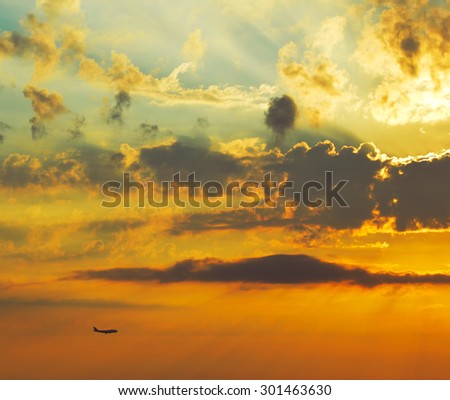 Silhouette of flying airplane on the background of beautiful cloudy sunset